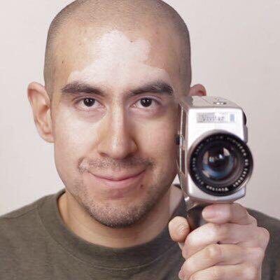 Juan Alcazar looking straight on with movie camera in hand.